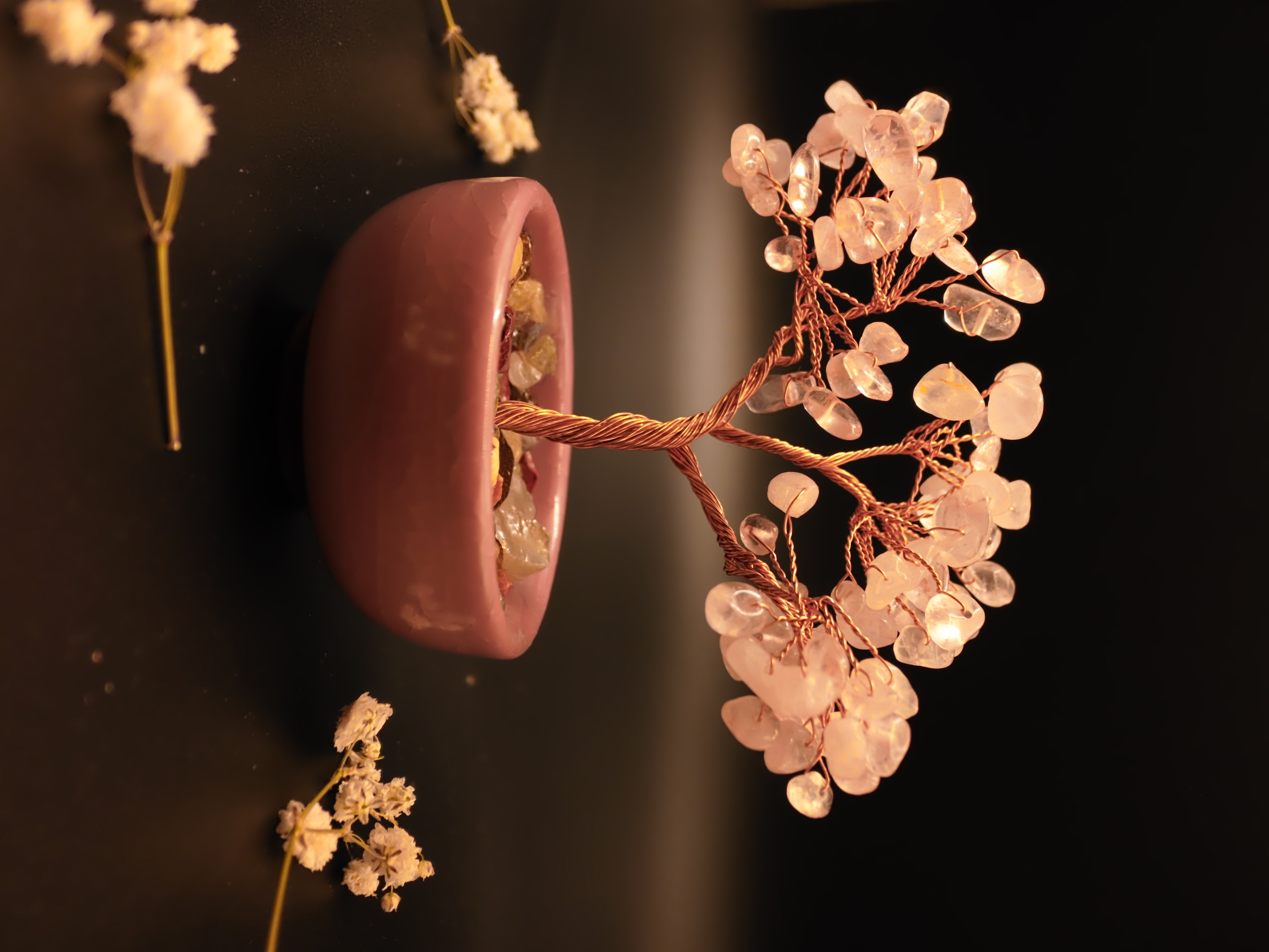 Rose quartz bonsai tree styled with dried flowers on dark background